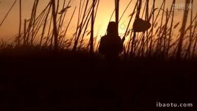 梦幻女孩的剪影与心形气球站在甘蔗田观看美丽的日落
